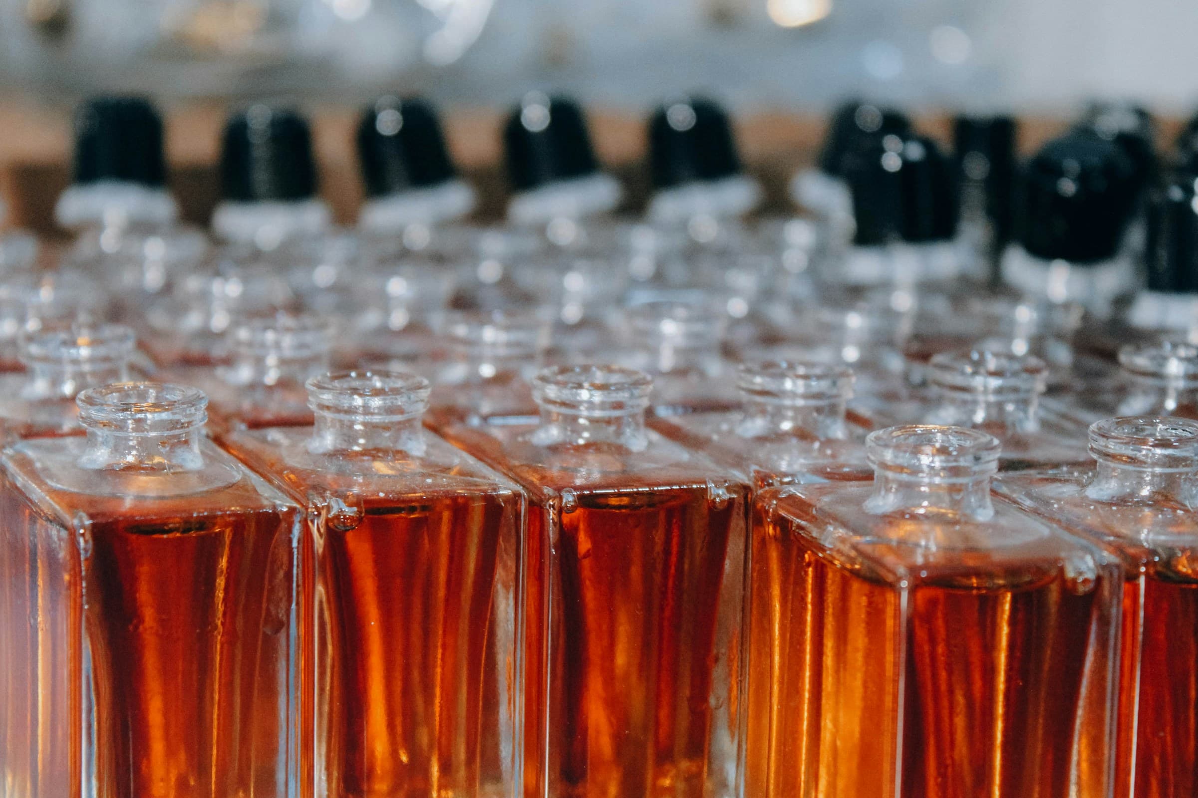 Rows of amber fragrance bottles prepared in a perfumery