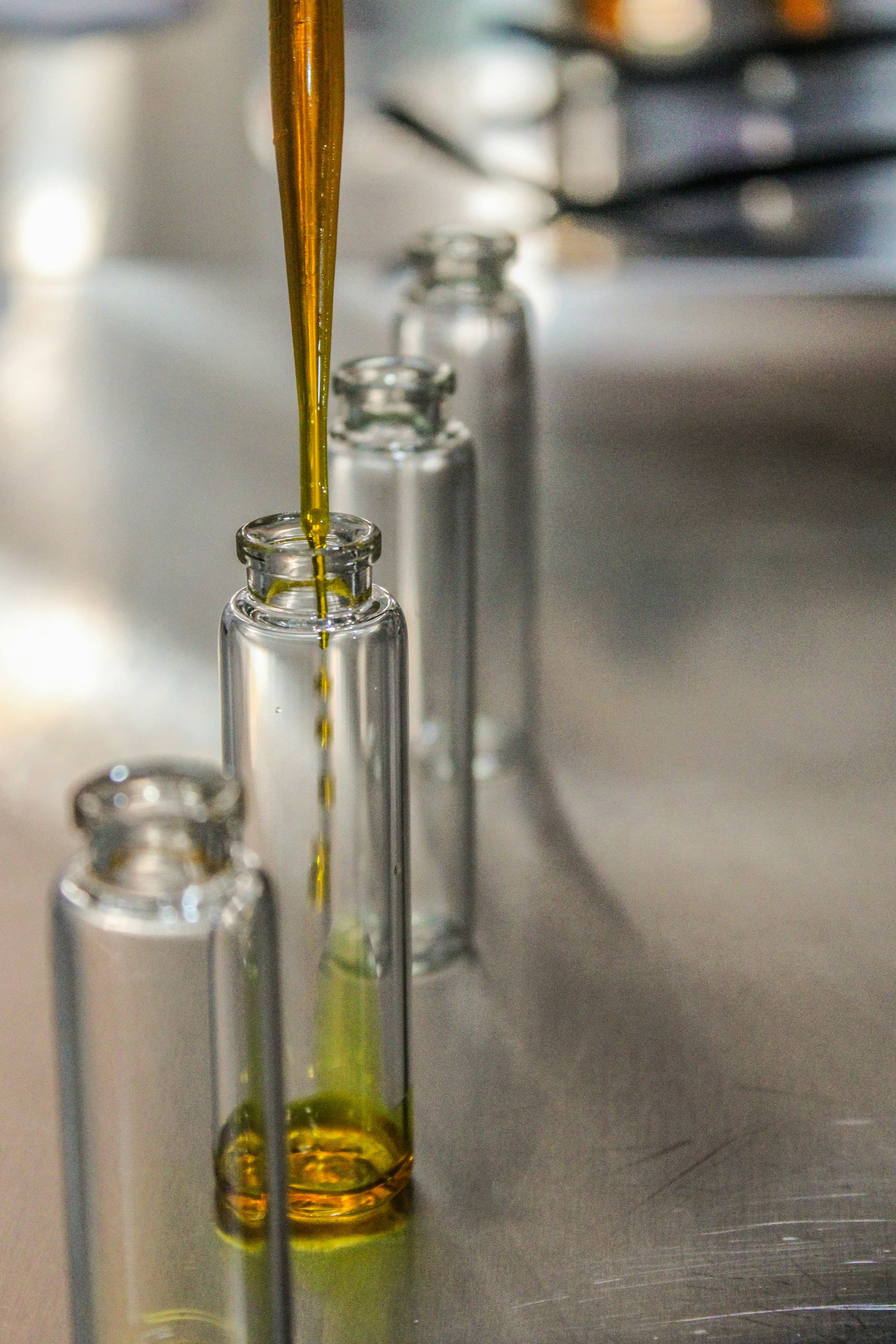 Golden fragrance oil being pipetted into clear perfume vials
